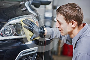 Auto mechanic buffing and polishing car headlight photo