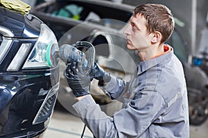 Auto mechanic buffing and polishing car headlight photo