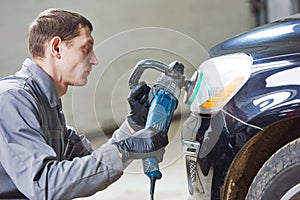 Auto mechanic buffing and polishing car headlight photo