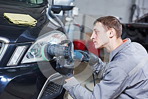 Auto mechanic buffing and polishing car headlight photo