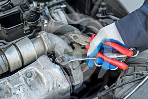 Auto mechanic in car repair holding wrench key and tools