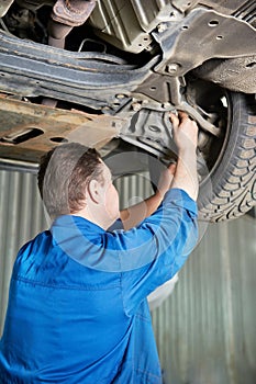 Auto mechanic at car suspension repair work