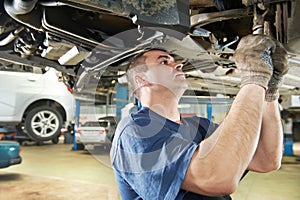 Auto mechanic at car suspension repair work