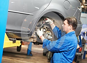 Auto mechanic at car suspension repair work