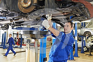 Auto mechanic at car suspension repair work