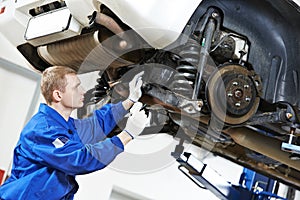 Auto mechanic at car suspension repair work photo