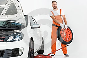 auto mechanic carrying car tire