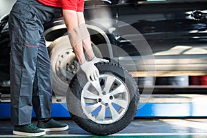 Auto mechanic carrying tire in tire store