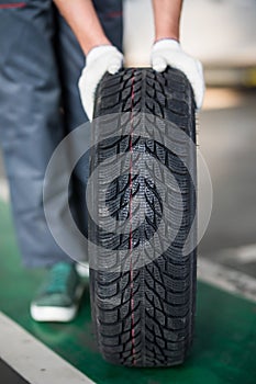 Auto mechanic carrying tire in tire store