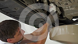 Auto mechanic changes oil filter under lifted car. Professional service tech replaces vehicle maintenance parts, employs