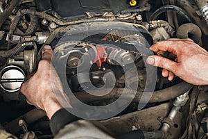 Auto mechanic changes the timing belt in the car photo