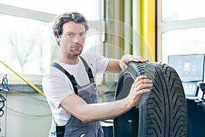 Auto mechanic changing tire in car workshop