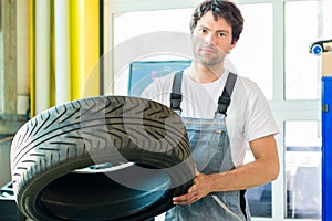 Auto mechanic changing tire in workshop