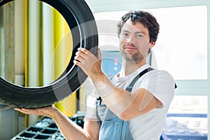 Auto mechanic changing tire in workshop