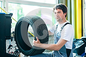 Auto mechanic changing tire in workshop