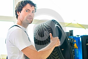 Auto mechanic changing tire in workshop