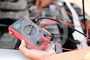 auto mechanic check car battery voltage by voltmeter multimeter