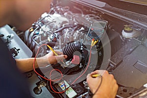 Auto mechanic checking car battery voltage