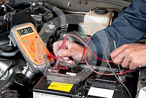 Auto mechanic checking car battery voltage photo