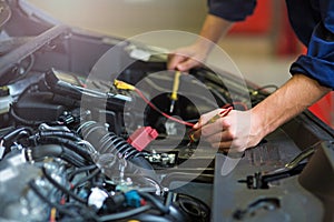 Auto mechanic checking car battery voltage