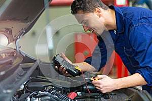 Auto mechanic checking car battery voltage