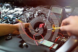 Auto mechanic checking car battery voltage