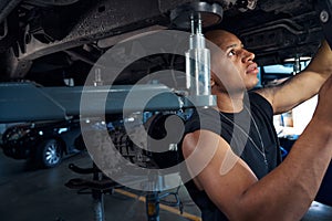 Auto-mechanic checking car-lift before lifting automobiles for maintenance