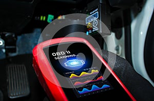 Auto mechanic checking ECU engine system with OBD2 wireless scanning tool and car information showing on screen interface