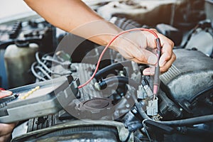 Auto mechanic checking electrical system in a car engine
