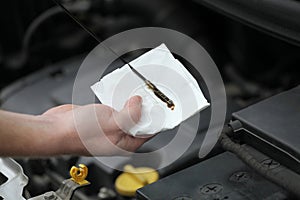 Auto mechanic checking engine oil dipstick in car