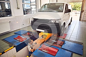 Auto mechanic checking running gear of automobile on service station. Male worker fixing problem with car. Vehicle maintenance