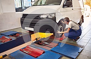 Auto mechanic checking running gear of automobile on service station. Male worker fixing problem with car. Vehicle maintenance