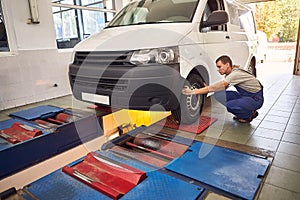 Auto mechanic checking running gear of automobile on service station. Male worker fixing problem with car. Vehicle maintenance