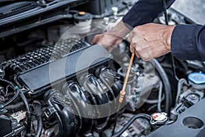 Auto mechanic checking vehicleâ€™s engine oil level to changing car engine oil