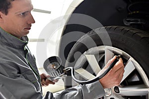 Auto mechanic checks the air pressure of a tire in the garage