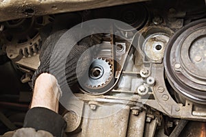 An auto mechanic checks the condition of an old timing belt during a technical inspection