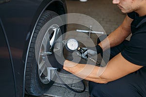 Auto mechanic checks the tire pressure in service