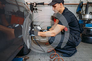 Auto mechanic checks the tire pressure in service