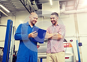 Auto mechanic with clipboard and man at car shop