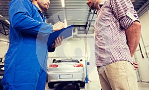 Auto mechanic with clipboard and man at car shop