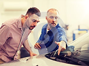 Auto mechanic with clipboard and man at car shop