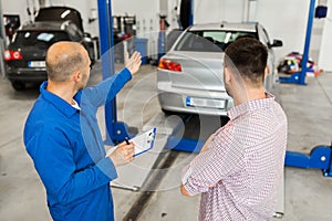 Auto mechanic with clipboard and man at car shop