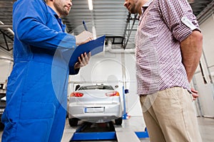 Auto mechanic with clipboard and man at car shop