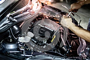 Auto mechanic hand fixing car engine in the garage