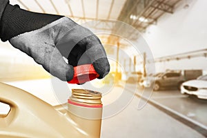 Auto mechanic hand is opening the cap of a gallon of motor oil in the auto repair shop