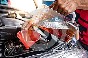 Auto mechanic hand pouring oil into car engine