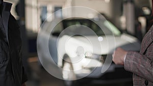 auto mechanic handing over car keys to a female client after repair and shaking hands close-up against the background of