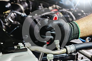 Auto mechanic hands in black gloves repairing a car engine. Car mechanic working on a car engine