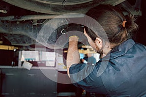 Auto mechanic handsome worker man checking wheel tires at garage, car service technician repairing customer car vehicle,
