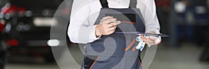 Auto mechanic holding clipboard and pen in car service